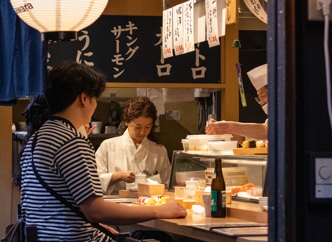 焼き台の前のカウンター席に座る客と、焼き手の店主