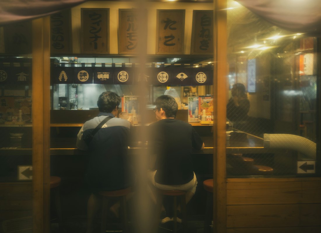 暖かい灯りの店内で、テーブルを囲む二人連れ