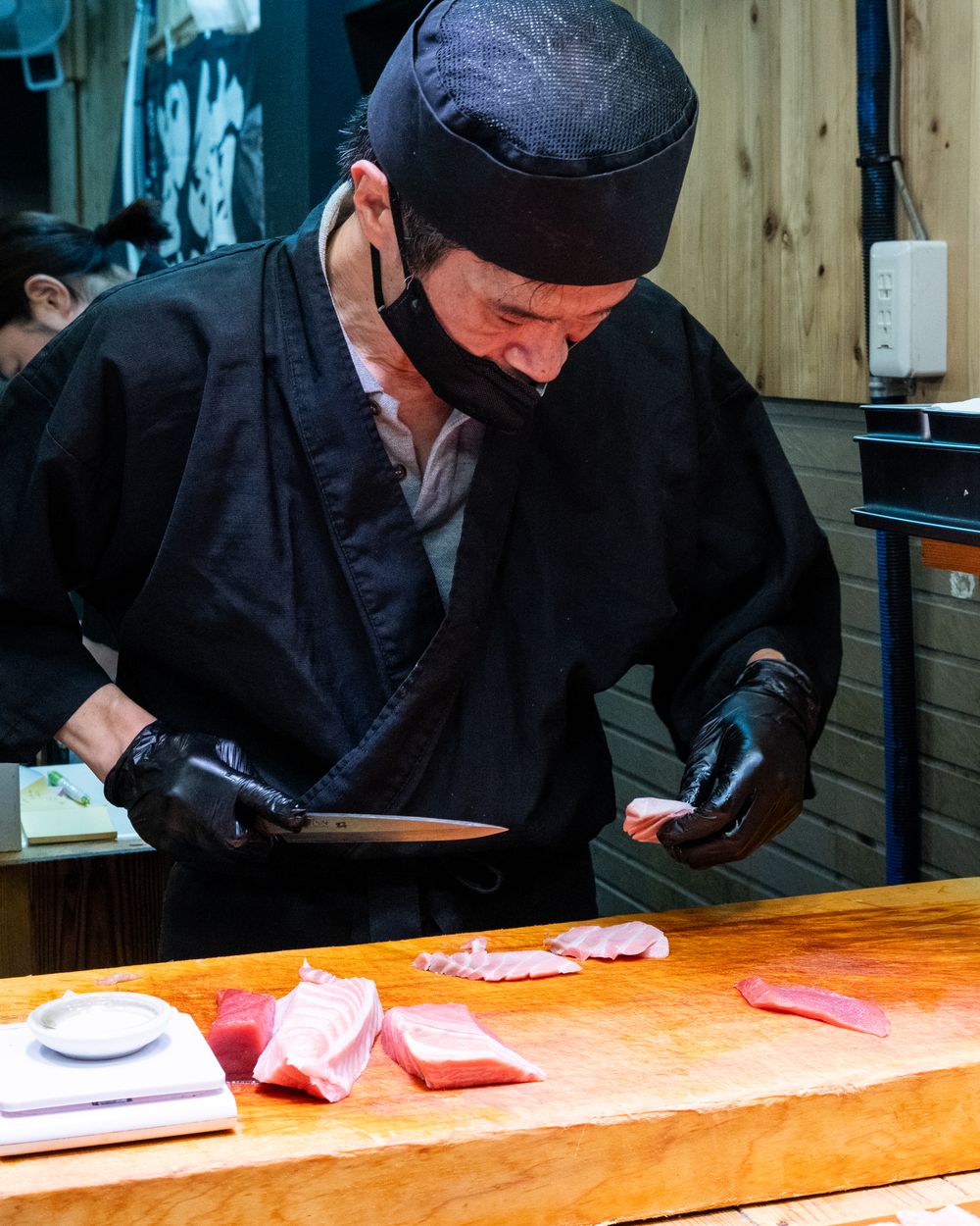 まな板に向かい、包丁で魚を切り分けている店主