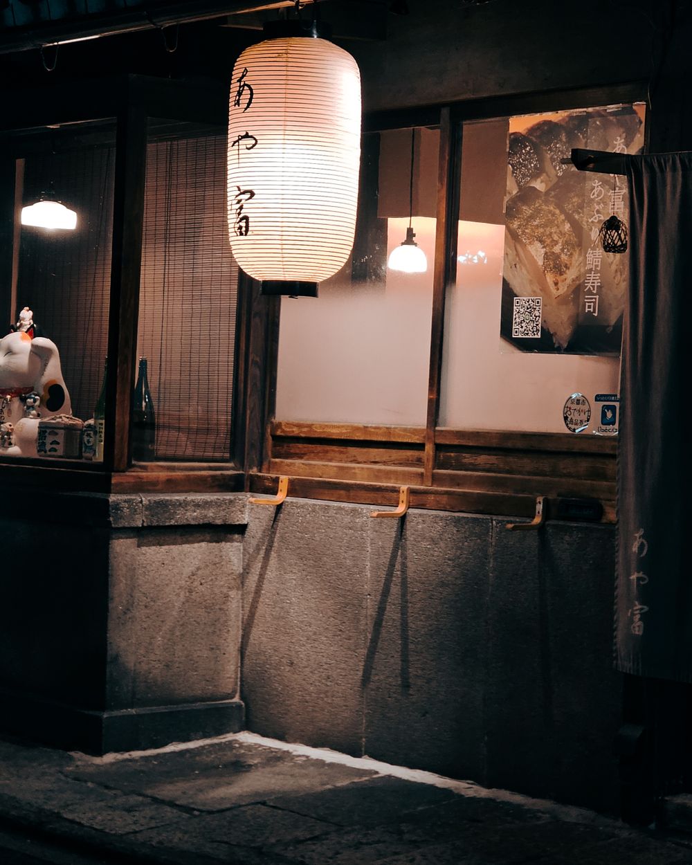 夜、灯りのついた入り口。暖簾と小さな行灯