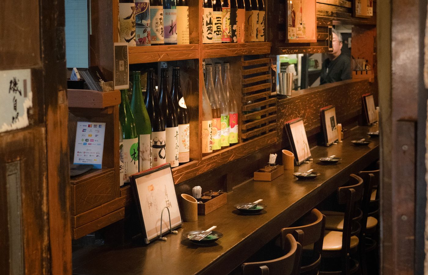 八席のカウンター。棚には、その日に開けている日本酒が並ぶ