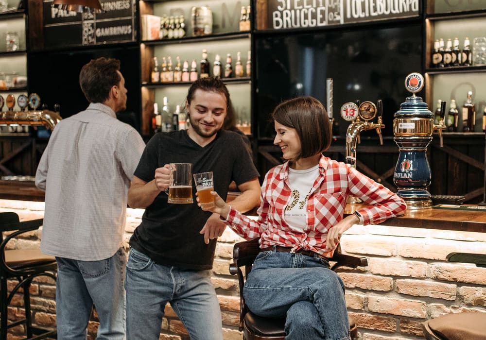 バーカウンターのそばで、ビールを手に談笑する若い人たち