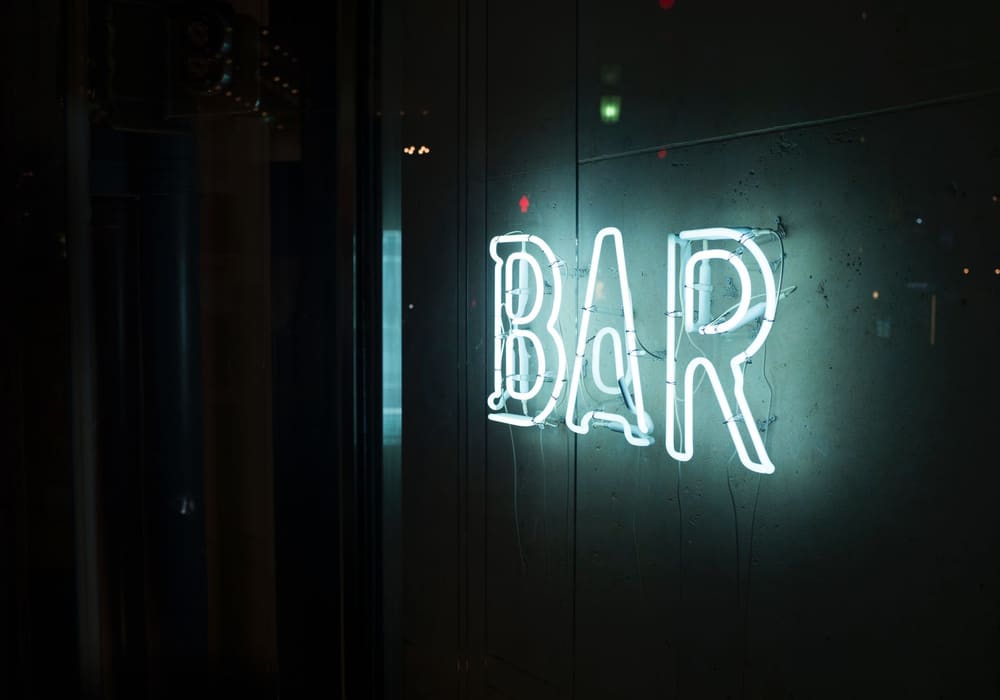 暗い壁に白く光る「BAR」のネオンサイン