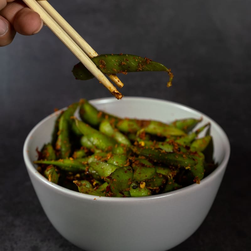 白い鉢の枝豆を、箸でつまむ手元
