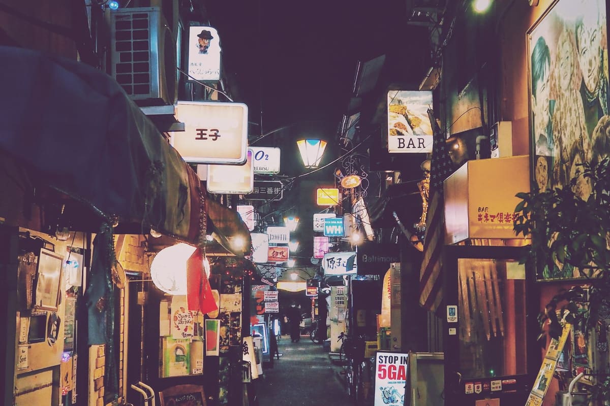 看板が並ぶ、紫がかった夜の路地