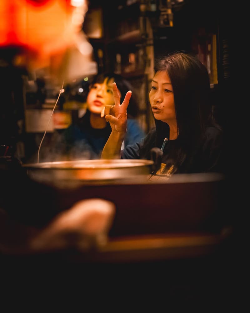 暖色の灯りの下で話す、2人の女性