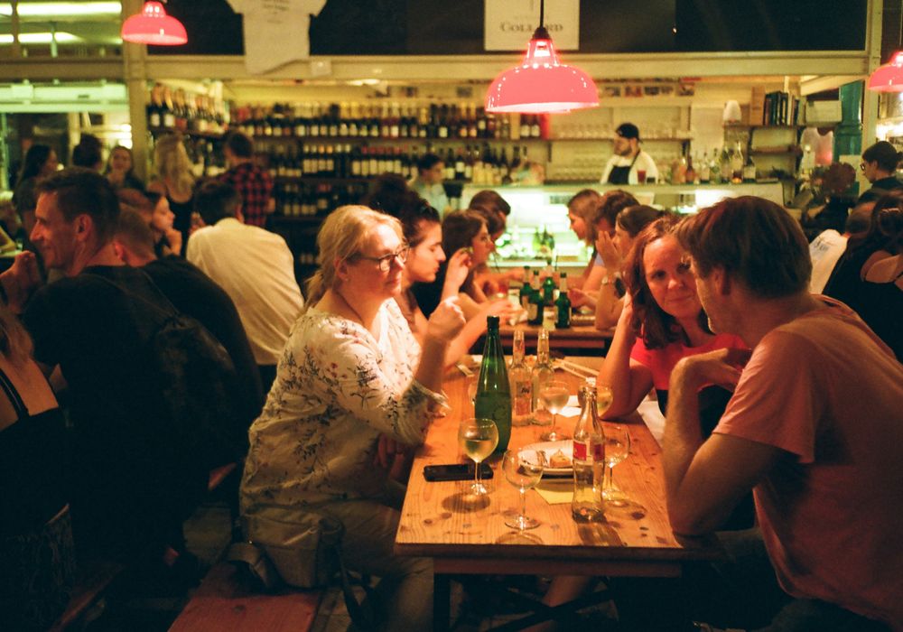 暖かい灯りの夜の店内で、テーブルを囲んで話す人たち