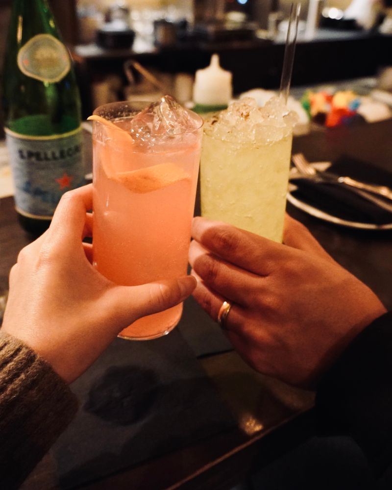 色の違うサワーを持って乾杯する2人
