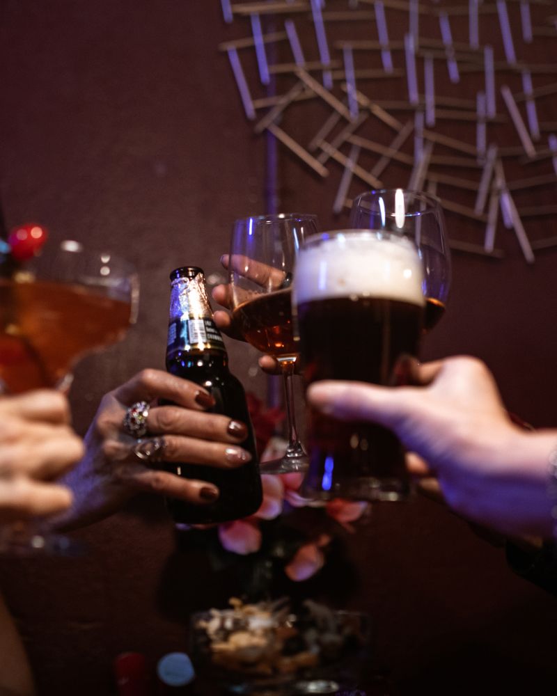 テーブルでビールを掲げて乾杯する友人同士