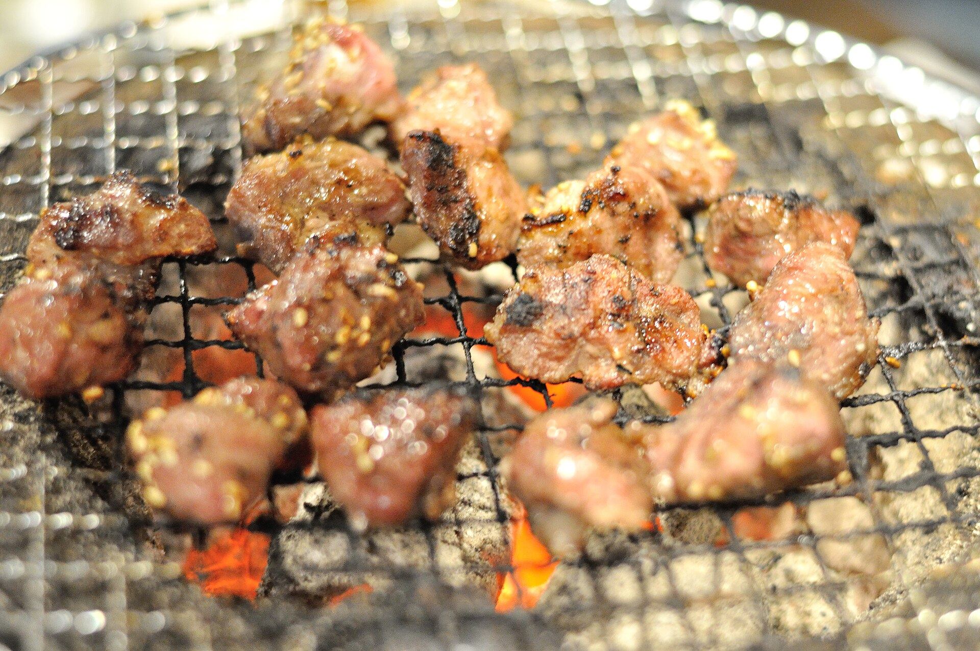 炭火の上で焼かれる、香ばしいカットステーキ肉
