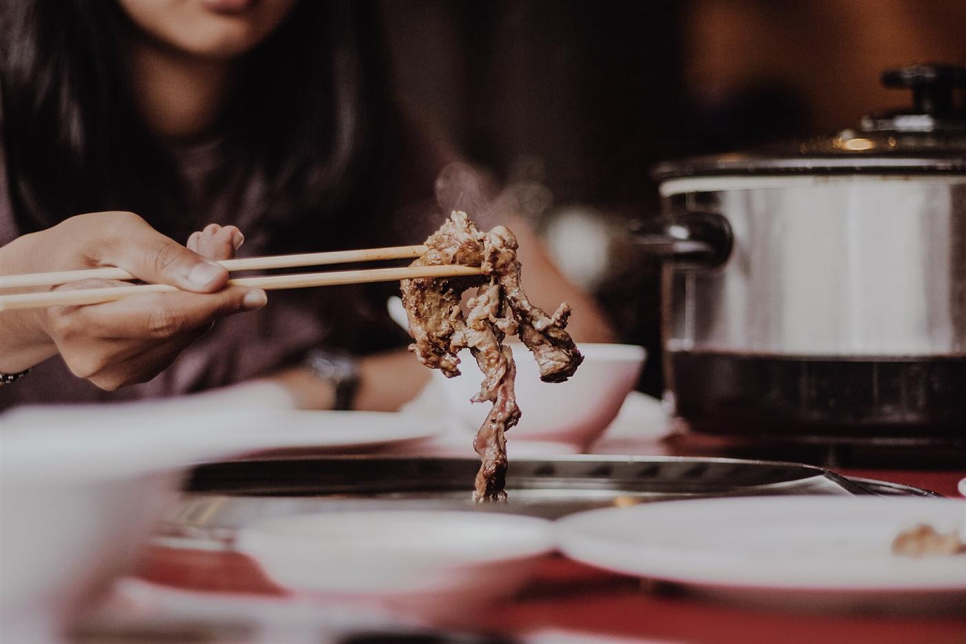 箸で肉をつまむ、ふたりの食卓