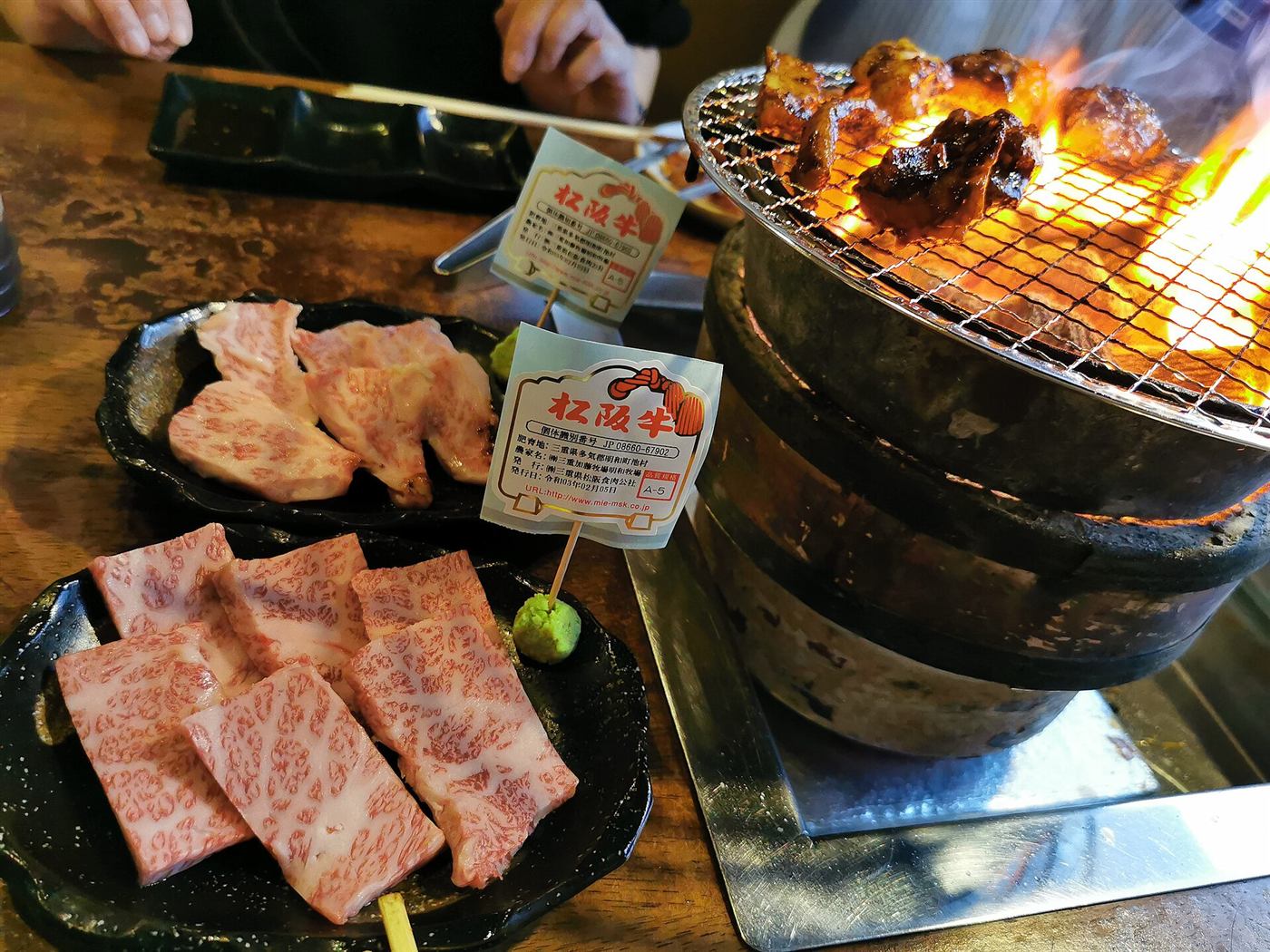 炎が立ちのぼる炭火と、テーブルに並ぶ肉